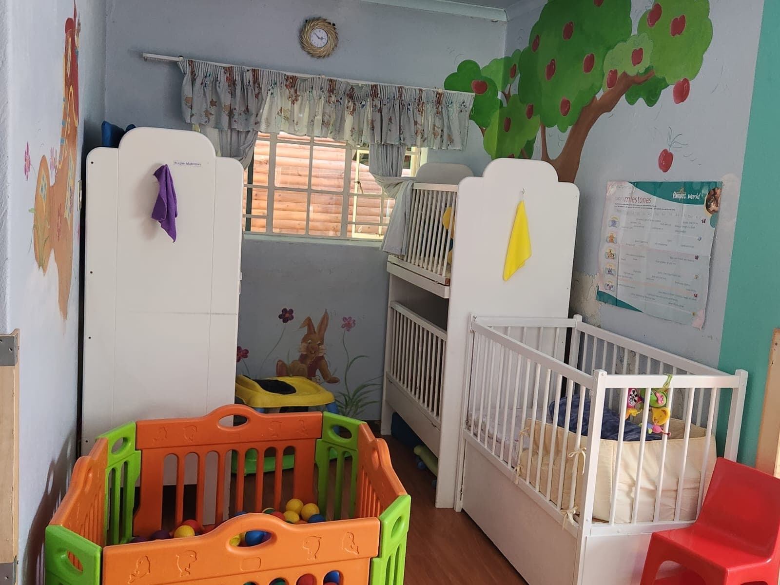 A Tiny Town baby room with a cot, a ball-pit playpen and a painted tree mural