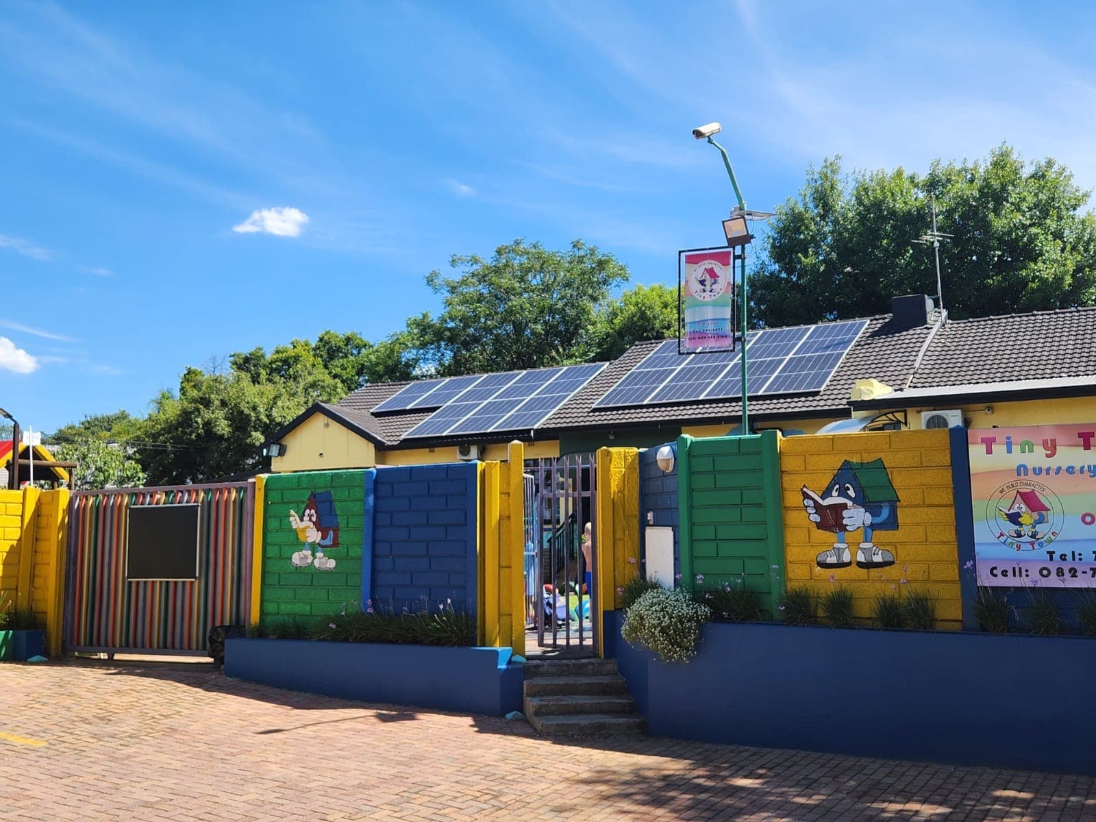 The Tiny Town building from the yard, with solar panels on the roof and murals along the wall