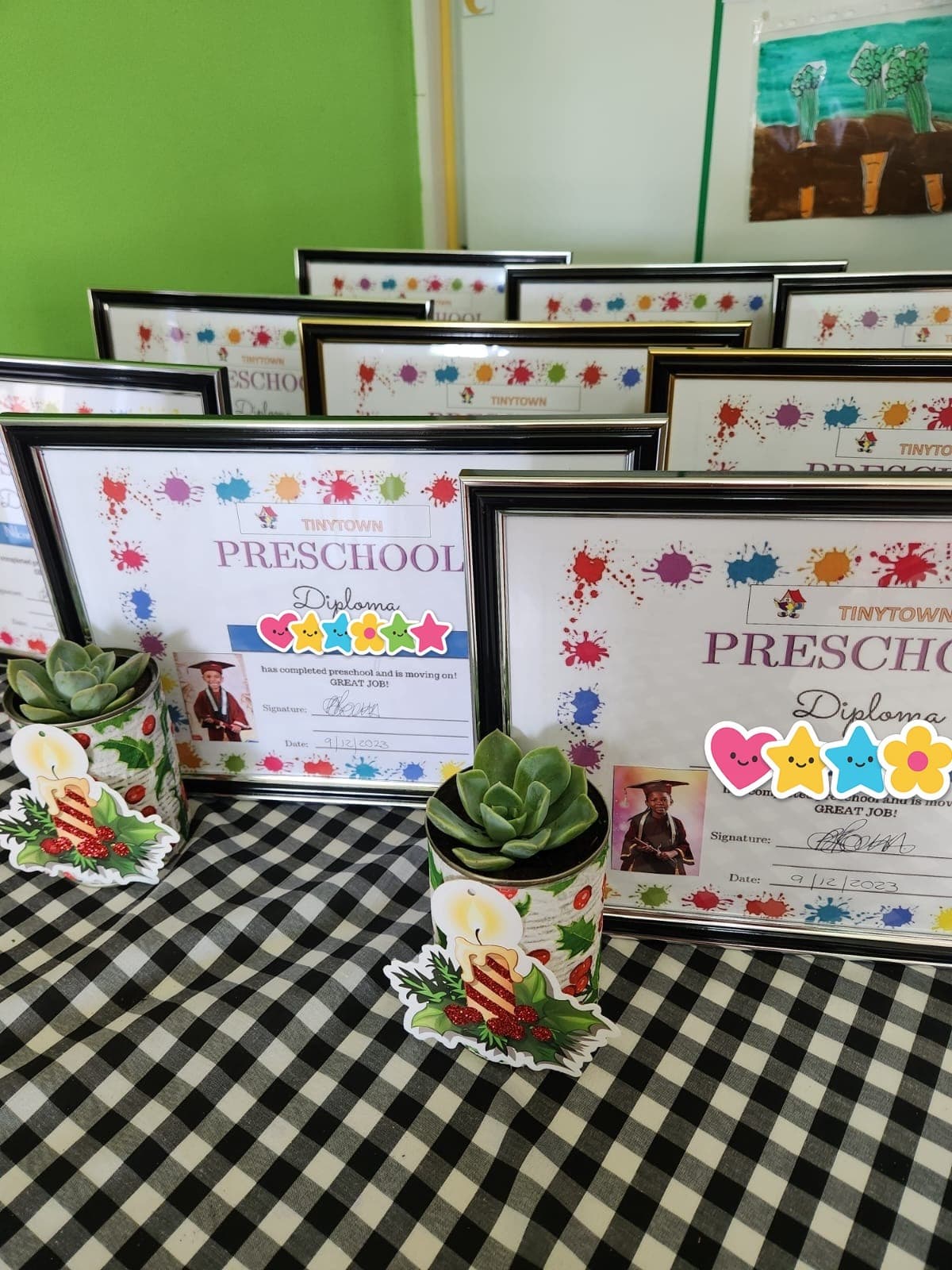 Framed Tiny Town preschool diplomas awarded to the school's graduates, with paper stickers covering the graduates' names